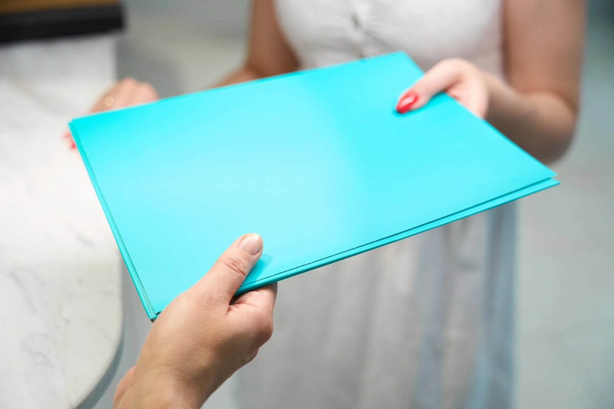 Une personne qui tend un dossier bleu à une autre