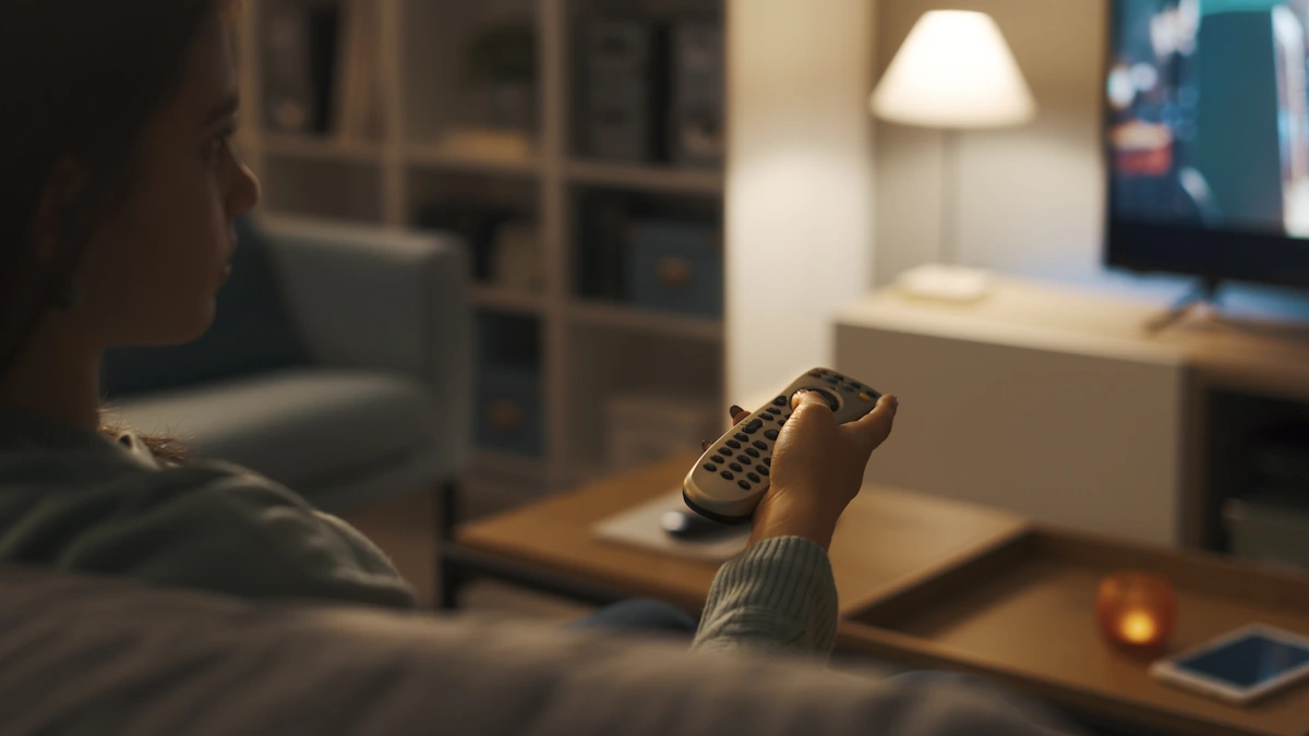 Un homme qui tient une télécommande dans un salon avec la télé et les lumières allumés