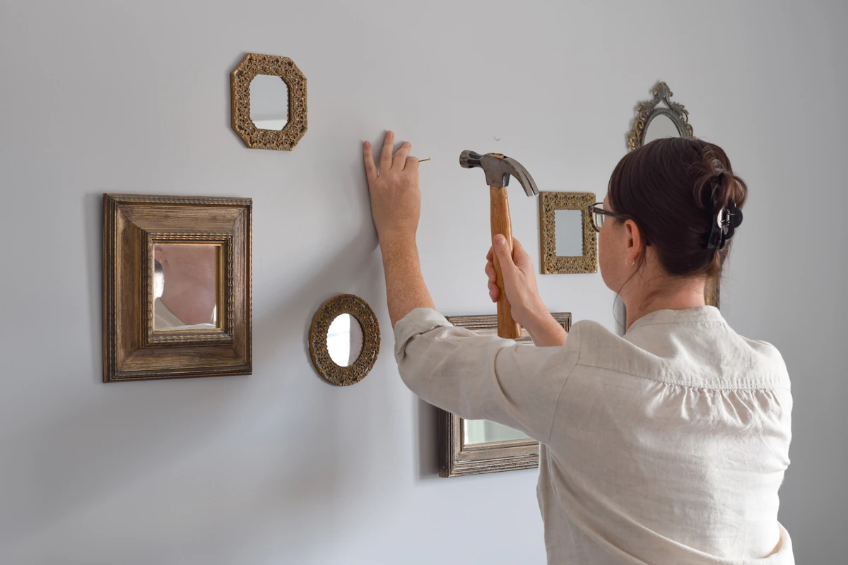 Une femme qui décorer un mur avec des cadres