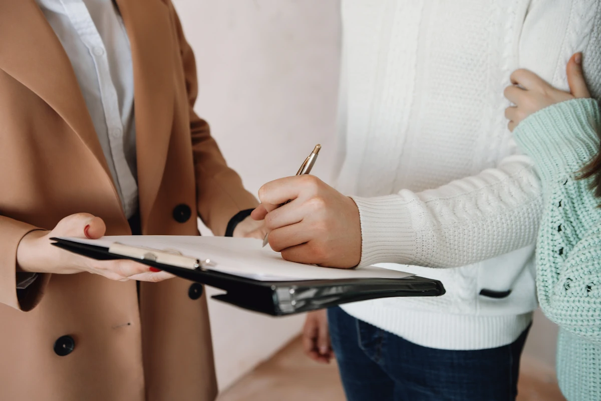 Une personne qui signe un document tendu par une autre personne