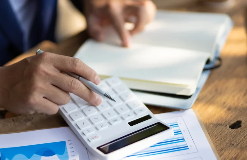 Une personne qui fait des calculs sur une calculatrice blanche