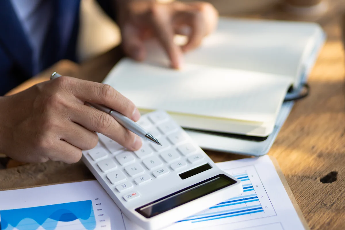 Une personne qui fait des calculs sur une calculatrice blanche