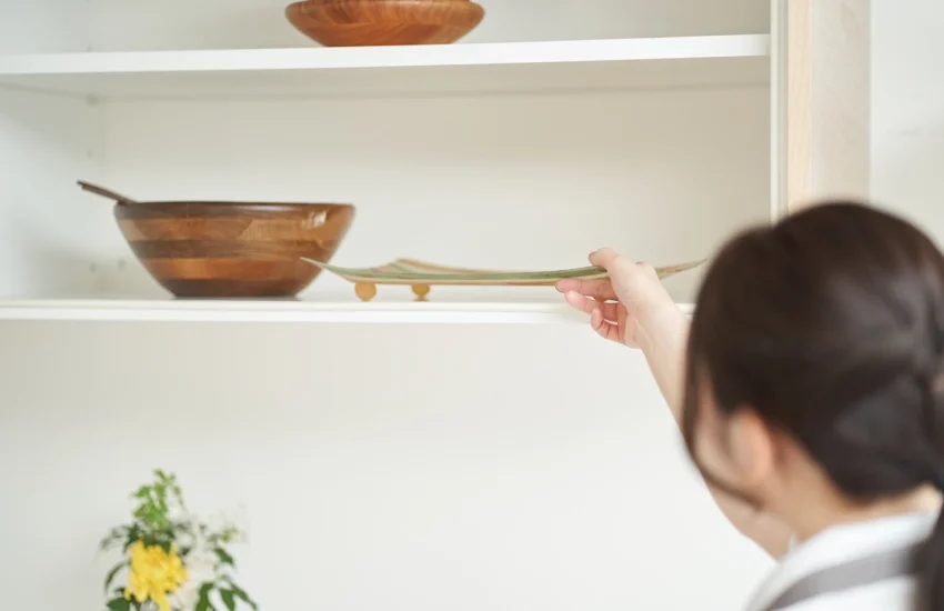 Une jeune femme qui pose un accessoire de décoration su rune étagère