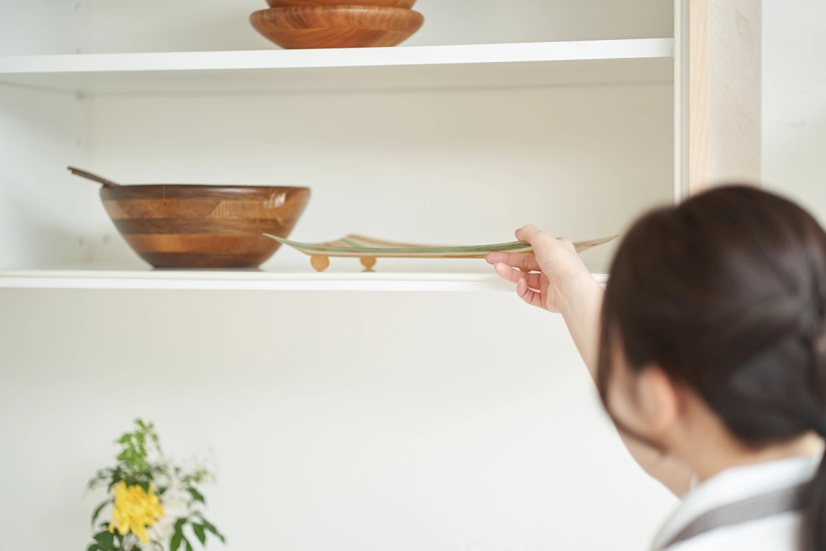 Une jeune femme qui pose un accessoire de décoration su rune étagère