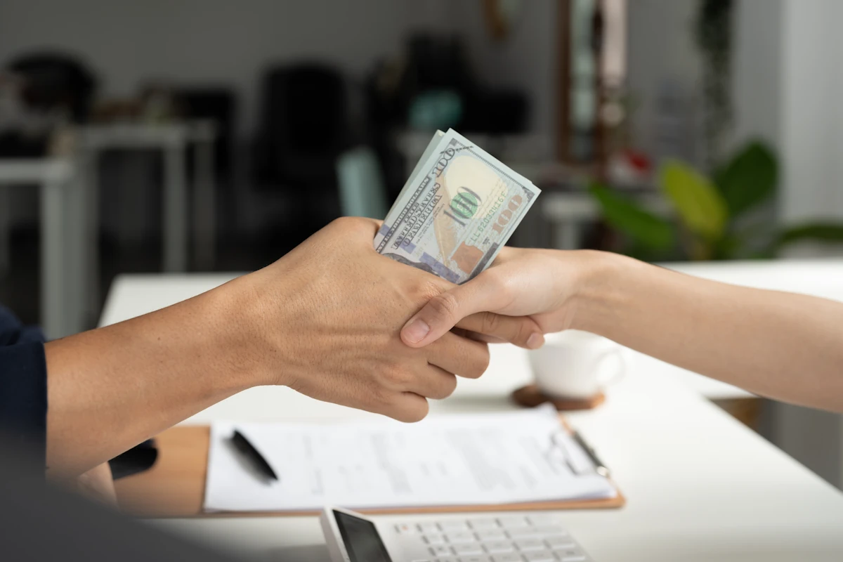 Une personne qui sert la main d'une autre avec de l'argent