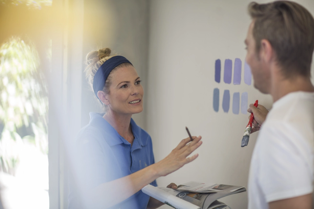 Une femme et un homme qui discute en face de quelques idées de couleurs de peinture sur un mur