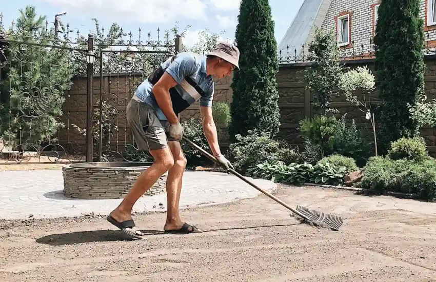 Une personne qui prépare le sol avant la pose d'une terrasse