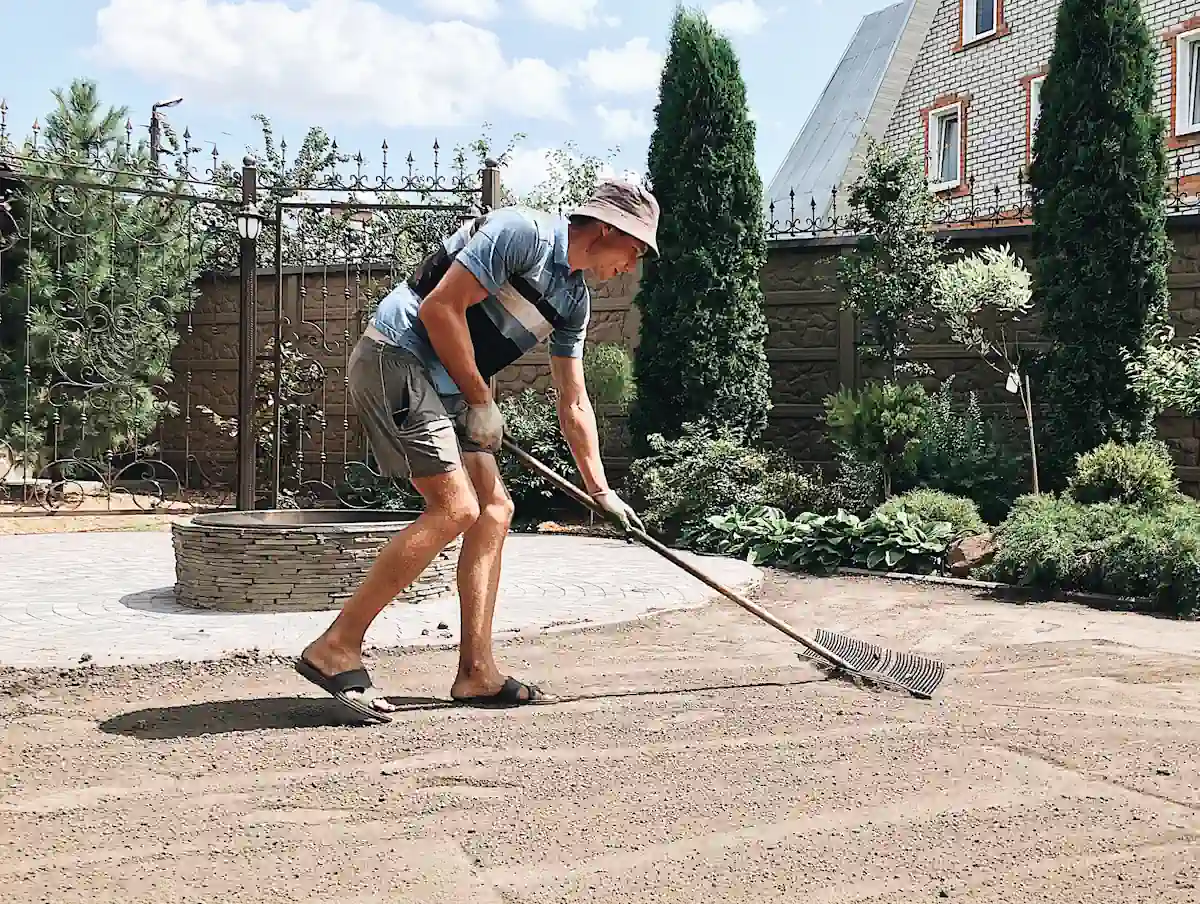 Une personne qui prépare le sol avant la pose d'une terrasse