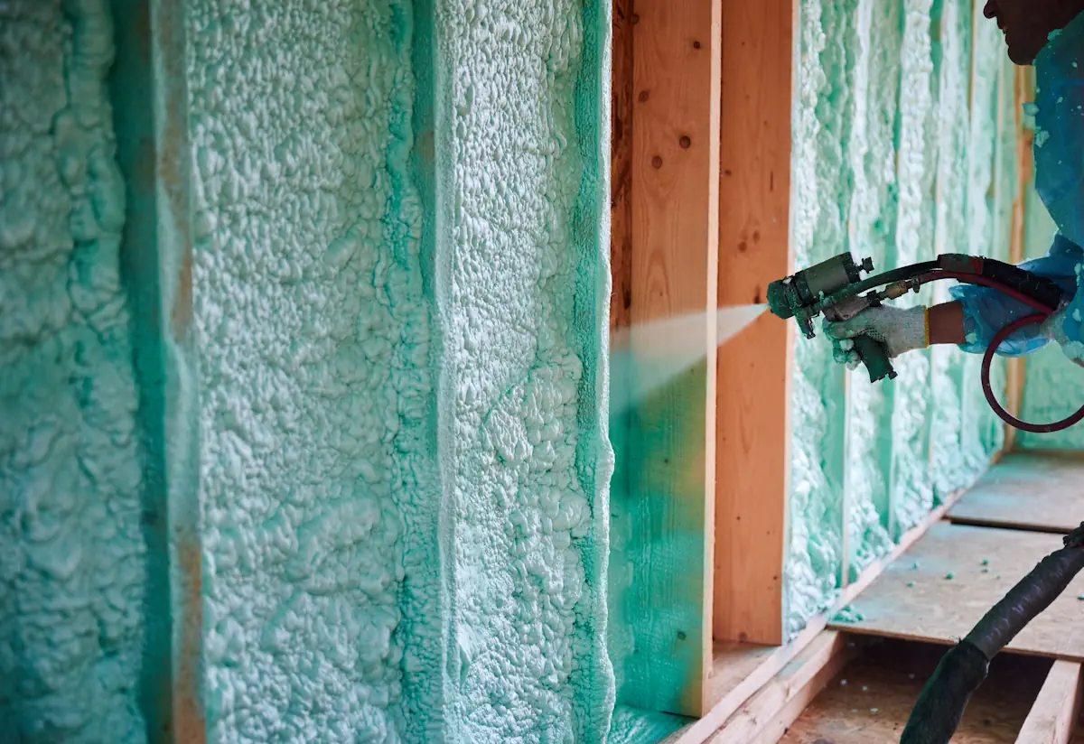 Une personne qui applique de la mousse polyuréthane sur un mur en bois